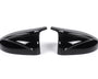 Two sleek black car side mirror covers face each other, reflecting light. They rest on a plain white background, showcasing their glossy finish and aerodynamic design.