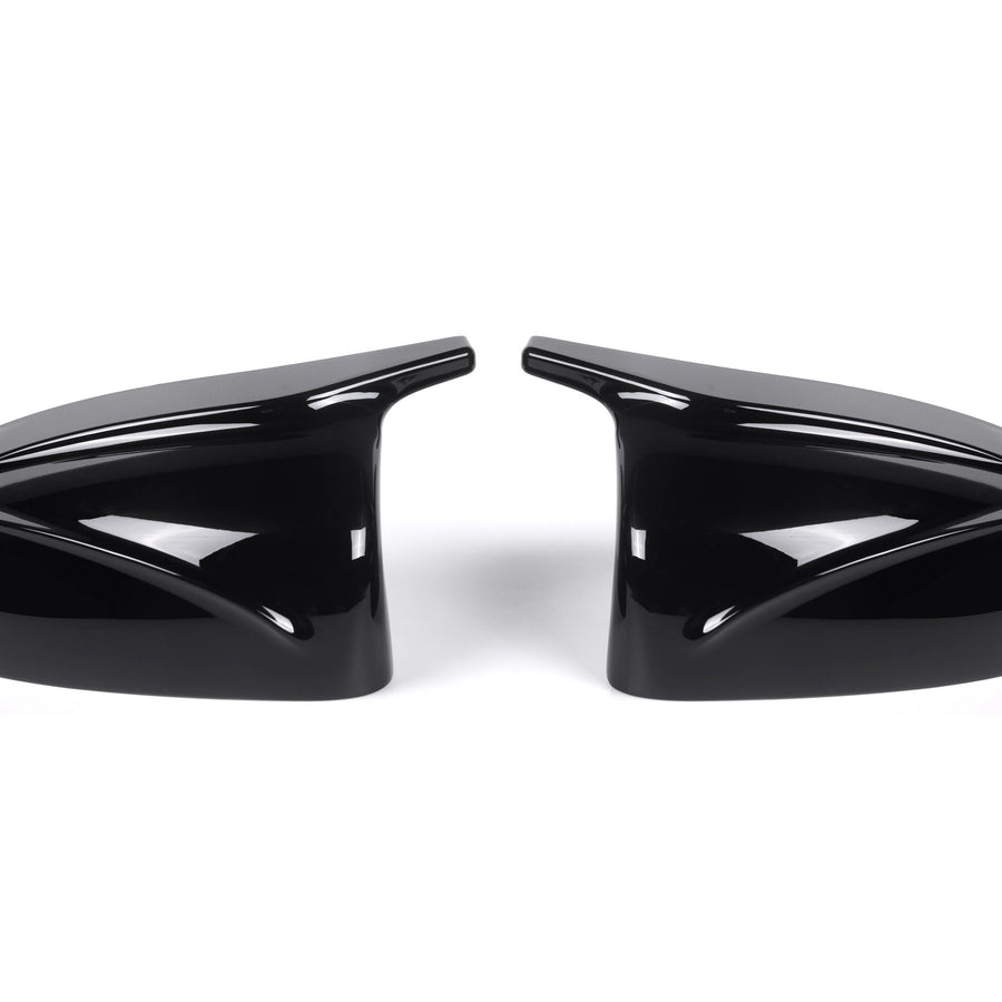 Two sleek black car side mirror covers face each other, reflecting light. They rest on a plain white background, showcasing their glossy finish and aerodynamic design.