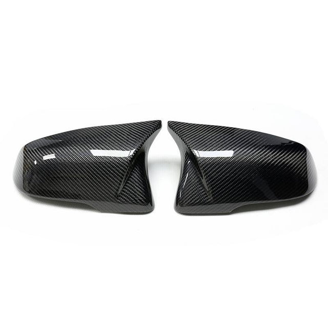 Two glossy carbon fiber car mirror covers, facing each other, are placed on a white background, highlighting their sleek and modern design.