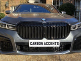 A BMW car parked on a gravel driveway features a prominent grille. The number plate reads 