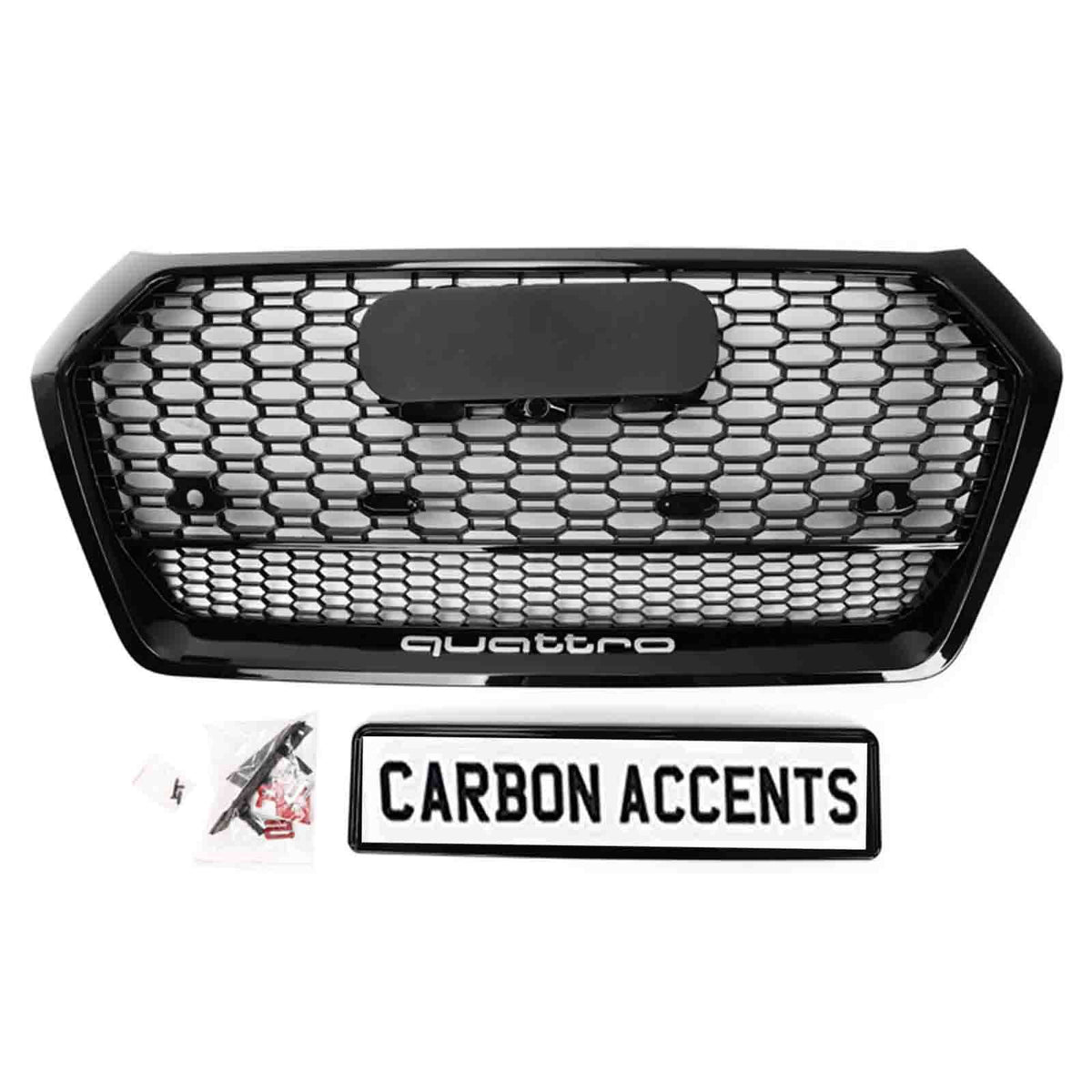 A black honeycomb car grille labeled "quattro" sits on a white background. Below it, a rectangular sign reads "CARBON ACCENTS," accompanied by several small plastic bags with parts.
