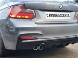 A gray BMW car is parked, displaying dual exhausts below a license plate reading 