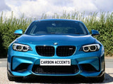 A blue sports car is parked on a gravel driveway, facing forward, with 