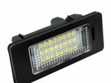 A rectangular LED light with a black frame angles upwards in a plain, white background, showcasing a grid-like lens covering an array of small yellow diodes.