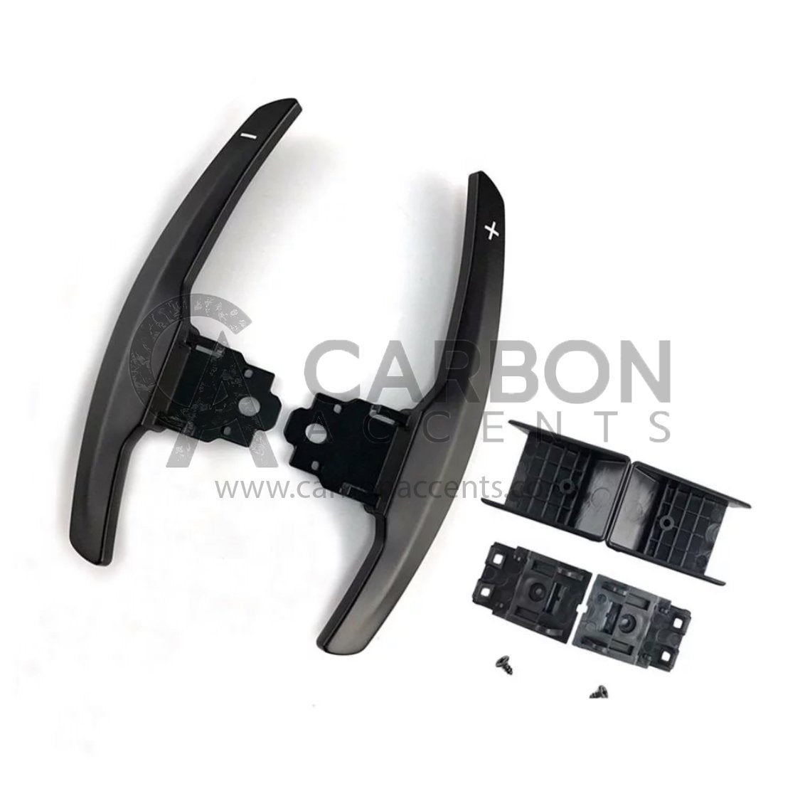 Curved paddle shifters with "+" and "-" symbols, accompanied by brackets and screws, are laid out on a white background. Text: "CARBON ACCENTS www.carbonaccents.com".