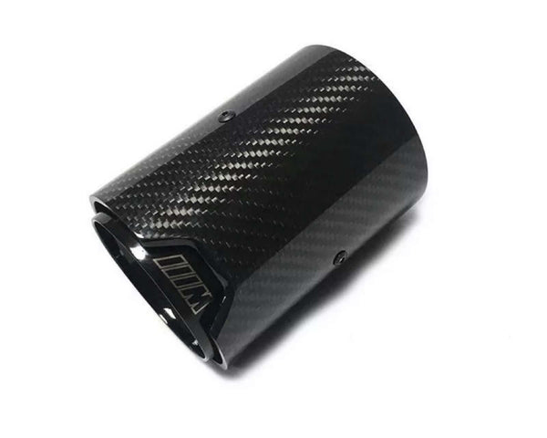 A carbon fiber exhaust tip lies against a plain white background. The surface has a textured pattern. The inner edge features a logo or marking resembling "///M."