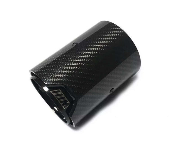 A carbon fiber exhaust tip lies against a plain white background. The surface has a textured pattern. The inner edge features a logo or marking resembling "///M."