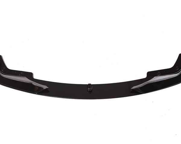 A sleek, black car front lip spoiler, resting on a white background, showcasing its aerodynamic shape with curved ends and bolt fixtures.