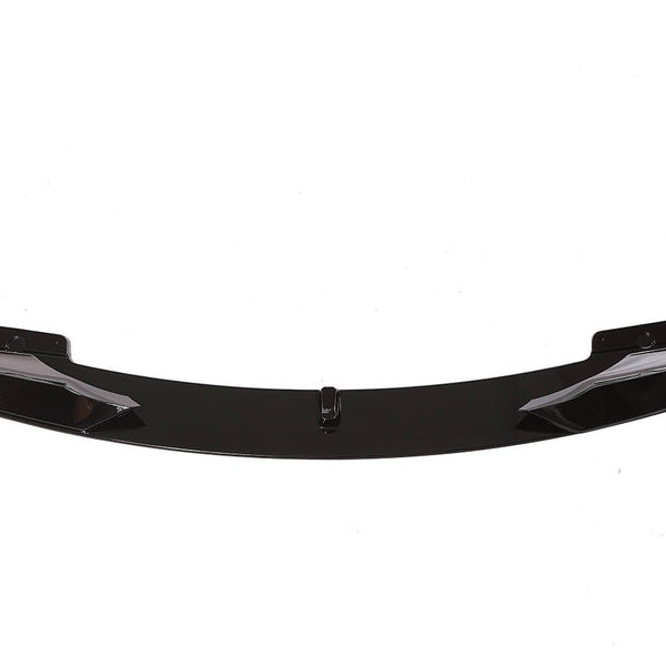 A sleek, black car front lip spoiler, resting on a white background, showcasing its aerodynamic shape with curved ends and bolt fixtures.