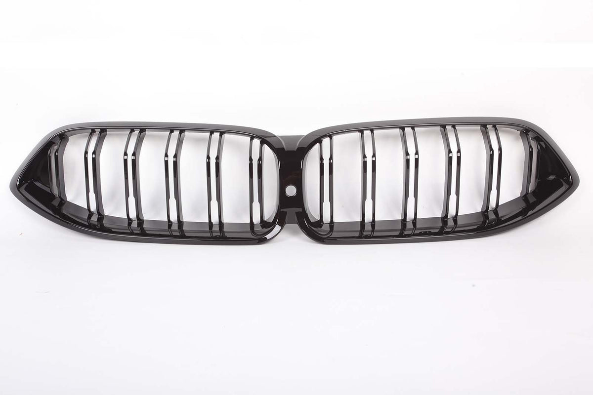 A glossy black car grille with vertical slats, designed in a double kidney shape, is placed against a plain white background.