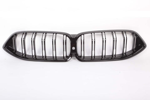 A glossy black car grille with vertical slats, designed in a double kidney shape, is placed against a plain white background.