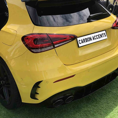 Yellow car parked on grass, featuring tinted windows and sleek tail lights. The license plate reads "CARBON ACCENTS." The car has a sporty design with dual exhausts.