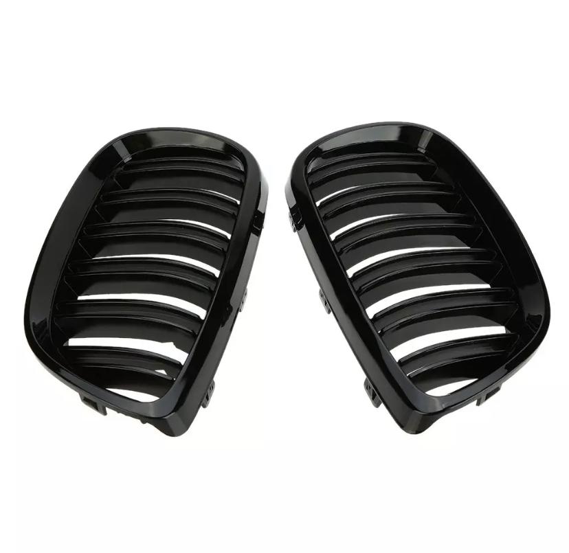 Two black, glossy car grilles with parallel slats are positioned side by side against a plain, white background, likely intended for vehicle front-end installation.