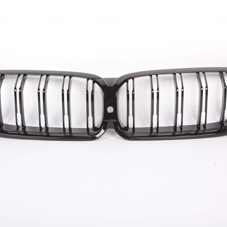 A black car grille with parallel vertical slats, forming a dual-kidney shape, is centered on a plain white background.