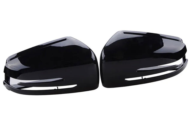 Two glossy black side mirror covers are positioned symmetrically, facing each other, against a plain white background.