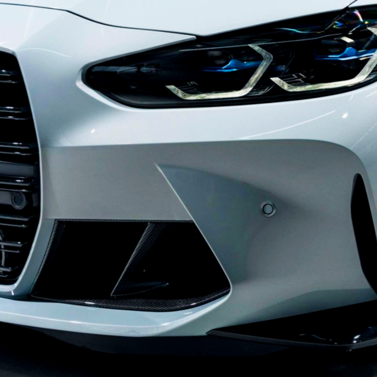 A modern car's front end with sleek headlights and prominent grille design, highlighted by a smooth, glossy surface in a well-lit, indoor environment.