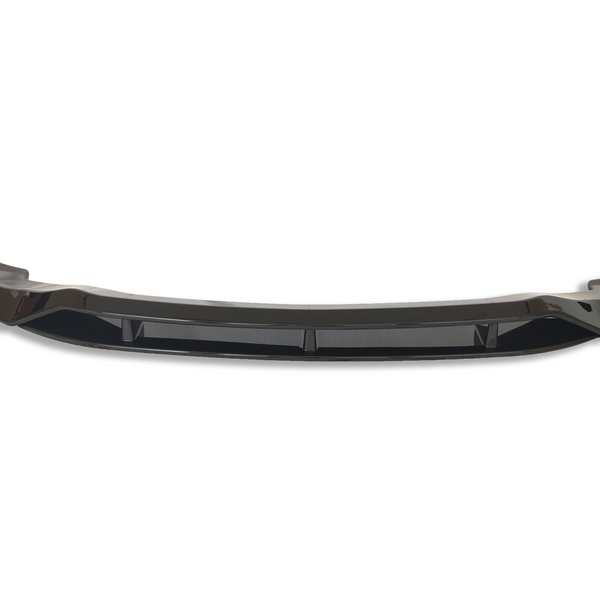 A glossy black car front bumper lip with aerodynamic curves sits isolated on a white background, emphasizing its sleek design and enhancing vehicle aesthetics and performance.