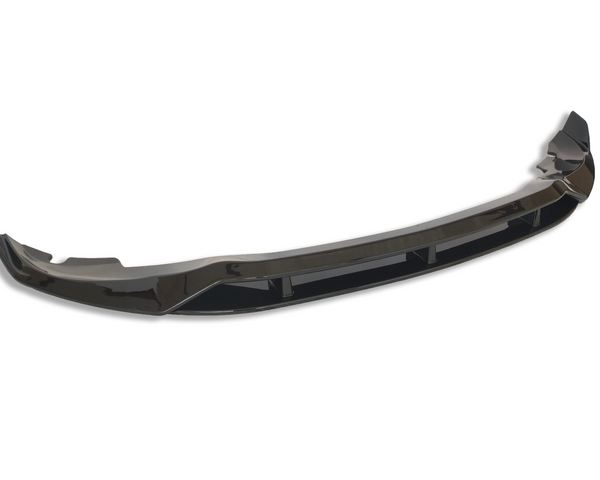 A glossy black car bumper lip sits isolated against a white background, showcasing its curved aerodynamic design and reflective surface.