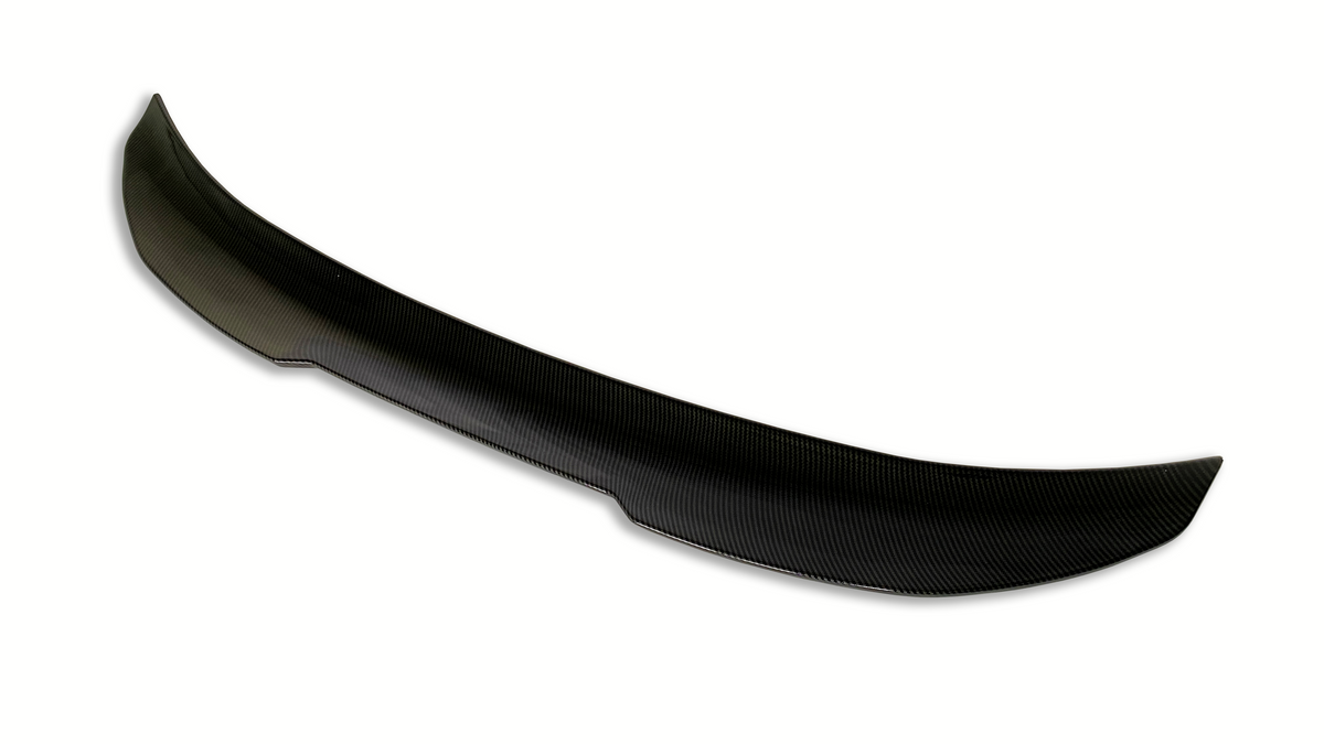A black carbon fiber car spoiler with a subtle curvature sits against a plain white background, highlighting its aerodynamic design.