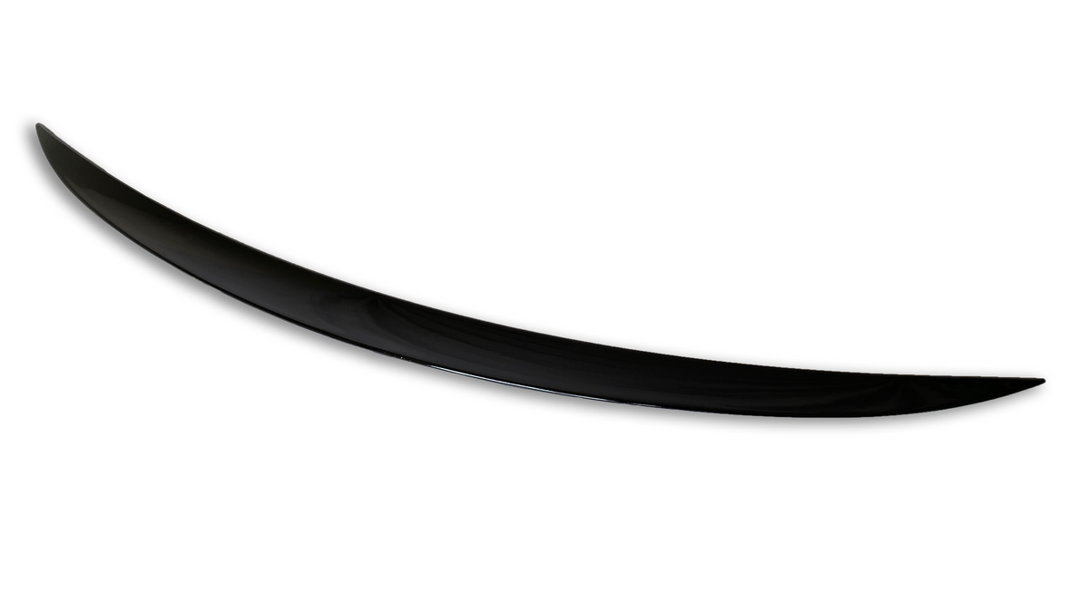 A sleek, elongated black object, resembling a boomerang or crescent shape, lies against a plain white background, its surface smooth and polished.