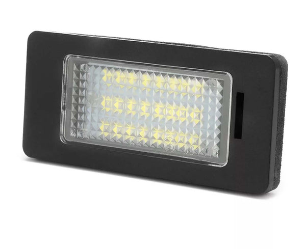 Rectangular LED light fixture angled slightly, featuring illuminated yellow diodes. It is encased in a black frame with a textured transparent cover, set against a plain white background.