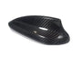 Carbon fiber car side mirror cover, sleek and glossy, lies on a white background, showcasing its weave pattern and aerodynamic shape.
