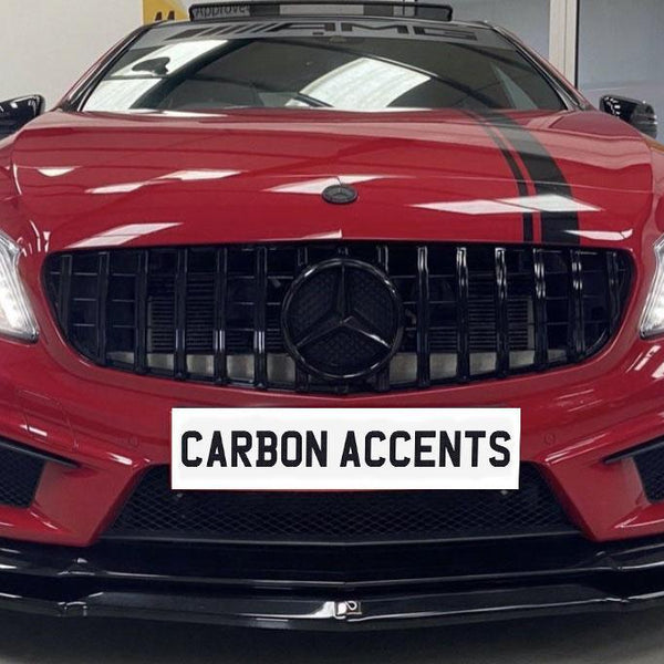 A red sports car with illuminated headlights is parked indoors, featuring black grille and stripes. A sign in front reads "CARBON ACCENTS." Decorative plants and another car are visible in the background.