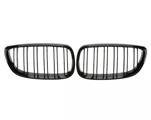 Two black car grille inserts with vertical slats are placed side by side against a plain white background, suggesting a symmetrical design typical of vehicle front ends.