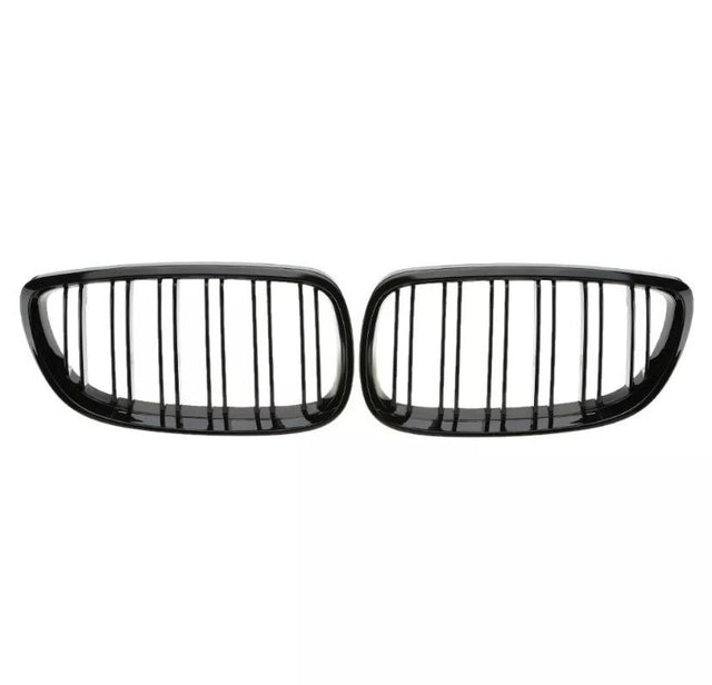 Two black car grille inserts with vertical slats are placed side by side against a plain white background, suggesting a symmetrical design typical of vehicle front ends.