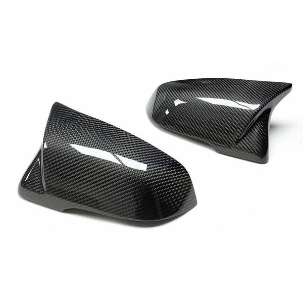 Carbon-fiber mirror caps, gleaming with a glossy surface, are positioned on a plain white background, showcasing their sleek, aerodynamic design.