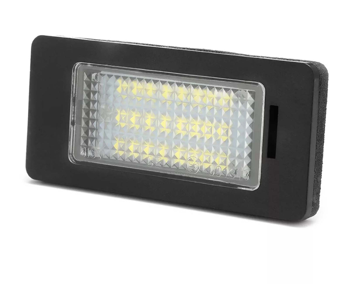 Rectangular LED light is shown, illuminated with multiple small yellow bulbs, encased in a textured clear cover. It's set in a black frame, likely suitable for automotive use.