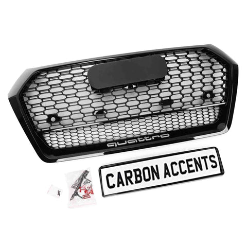 A hexagonal car grille with a honeycomb pattern labeled "quattro" includes mounting hardware. Below it, a framed sign reads "CARBON ACCENTS." The background is plain white.