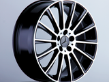A glossy black and silver alloy wheel with a star emblem rests on a pedestal, set against a plain light gray background.