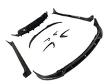 Several black car body kit components are spread out, including a front splitter, side skirts, and bumper lip, arranged on a plain white background.