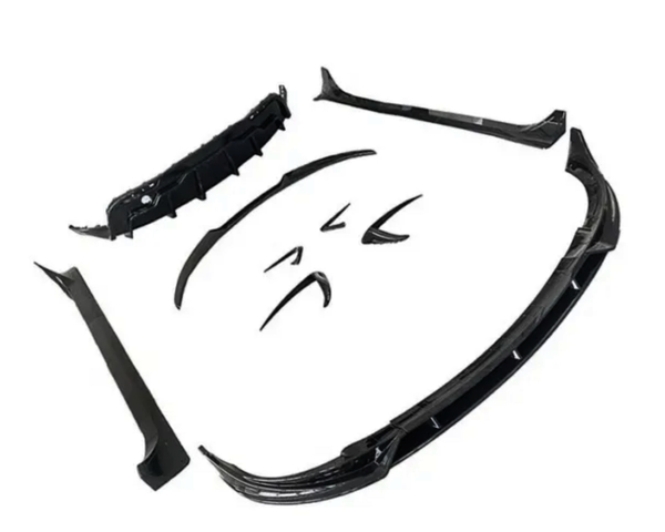 Several black car body kit components are spread out, including a front splitter, side skirts, and bumper lip, arranged on a plain white background.