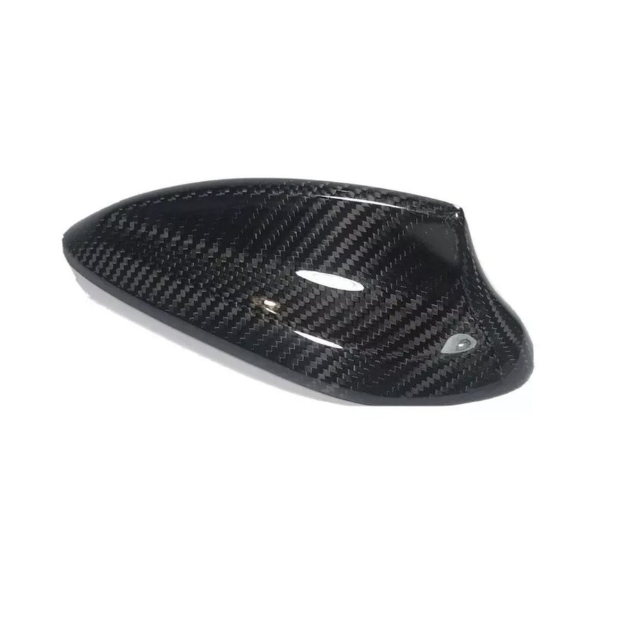 A carbon fiber car mirror cover, featuring a glossy, black textured surface, rests against a plain white background, highlighting its sleek design and curved aerodynamic shape.