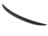 A sleek, black car spoiler lies on a plain white surface, curving slightly upward at the ends.