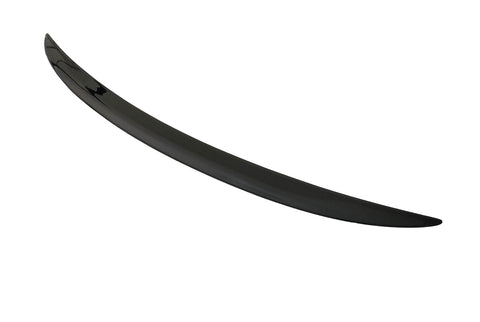 A sleek, black car spoiler lies on a plain white surface, curving slightly upward at the ends.