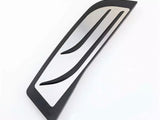 Curved metal vent with black trim, featuring two elongated slots parallel to its edges. It rests on a plain white surface.