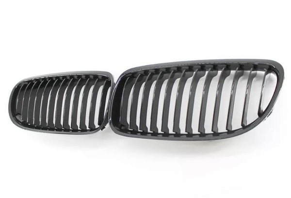 Two black car grille inserts with vertical slats lie side by side on a white background, resembling classic automotive front grille designs.