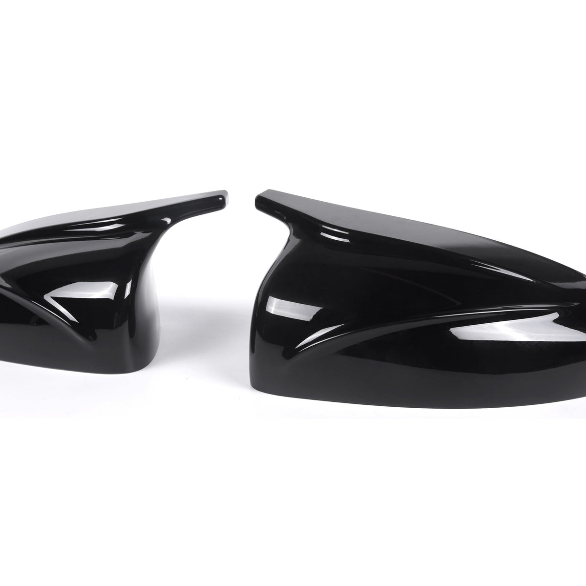 Two glossy black car mirror covers rest side by side, featuring sleek aerodynamic designs, set against a plain white background.