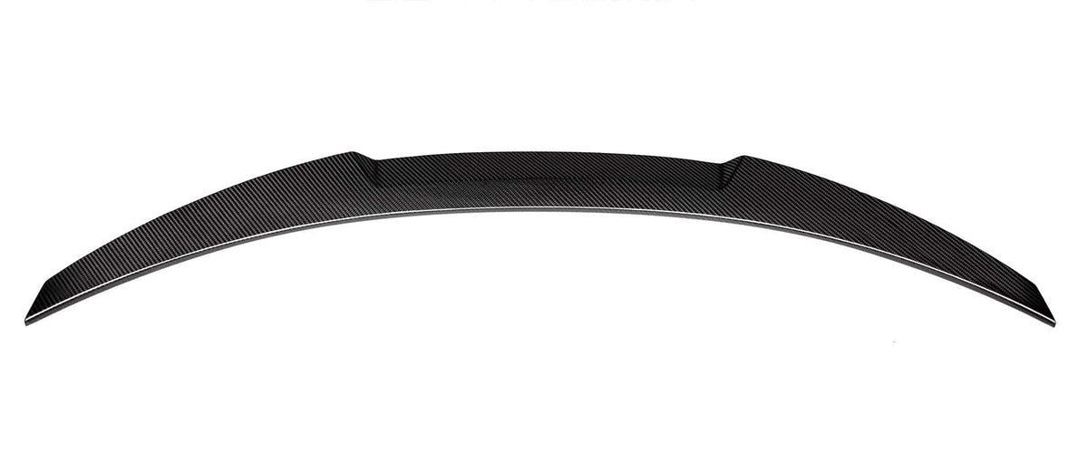 A curved carbon-fiber car spoiler rests against a plain white background, showcasing its textured, sleek design and aerodynamic build.