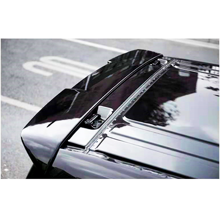 A black car roof with an attached roof rack is parked on a city street, with a blurred building and street marking visible in the reflection.