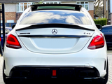 A white Mercedes-Benz AMG C43 parked on a driveway. The rear view shows badge logos and a clean, modern design. Houses and trees are visible in the background.