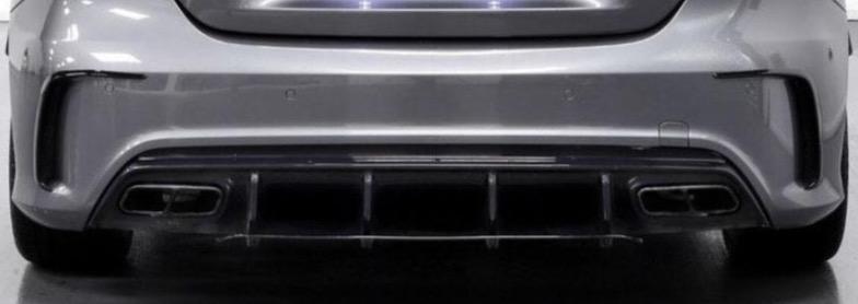 Rear view of a silver car features a sleek bumper, quad exhaust pipes, and a diffuser. The setting is an indoor showroom with a reflective floor surface.