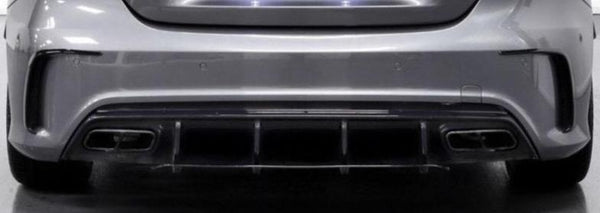 Rear view of a silver car features a sleek bumper, quad exhaust pipes, and a diffuser. The setting is an indoor showroom with a reflective floor surface.