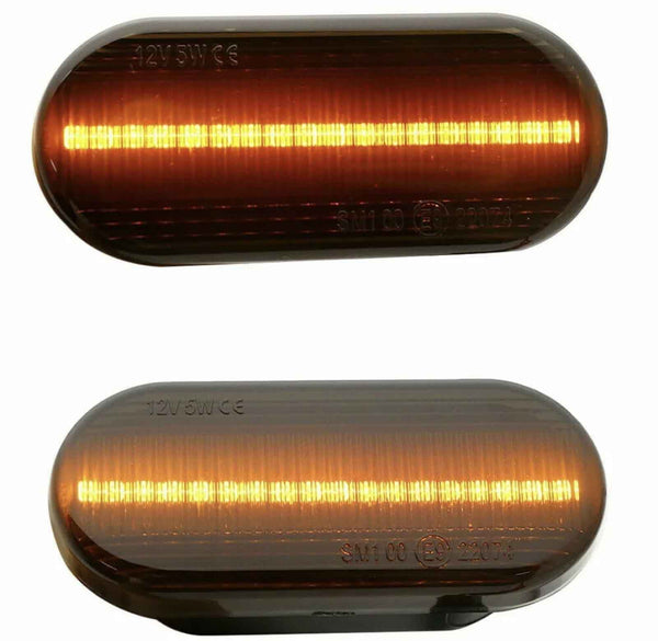 Two oval amber LED lights, one above the other, glow with horizontal strips of light. Both have inscriptions: "12V 5W E6" on the top left and "SM1 00 (E4) 23076" on the bottom.