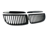 Two black, glossy, kidney-shaped car grilles with vertical slats are lying on a white background, separated into two symmetrical sections.
