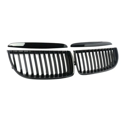 Two black, glossy, kidney-shaped car grilles with vertical slats are lying on a white background, separated into two symmetrical sections.