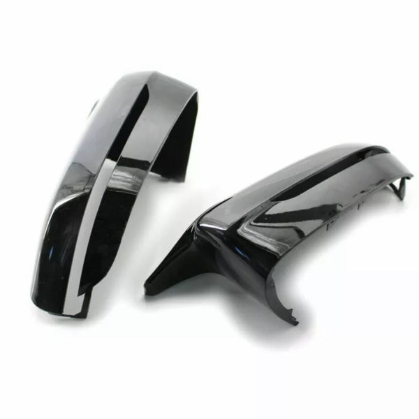 Two glossy black car mirror covers rest on a plain white surface, showcasing their sleek, curved design and reflective finish.